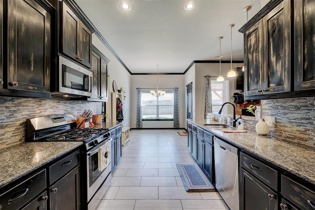 kitchen featuring pendant lighting, sink, appliances with stainless steel finishes, a notable chandelier, and light stone counters