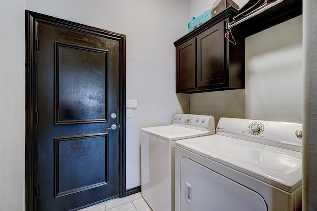 laundry area featuring washer and clothes dryer, light tile patterned flooring, and cabinets