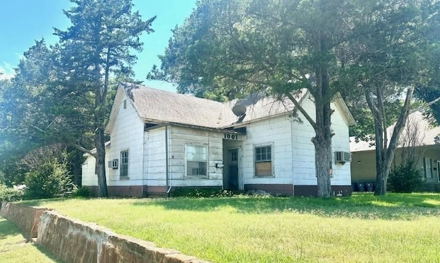 view of front facade featuring a wall mounted air conditioner and a front lawn