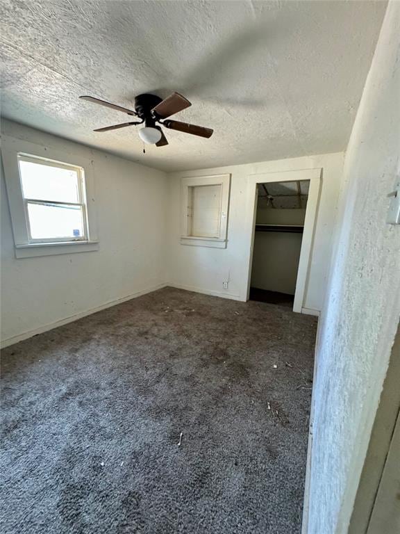 unfurnished bedroom featuring carpet, a textured ceiling, and ceiling fan