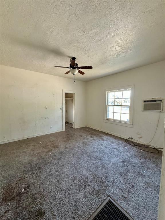 unfurnished bedroom featuring ceiling fan, a textured ceiling, a walk in closet, a closet, and carpet