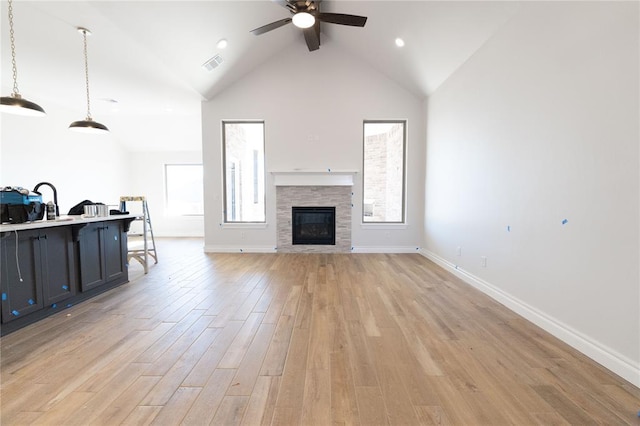 living room with visible vents, baseboards, ceiling fan, light wood-type flooring, and high vaulted ceiling