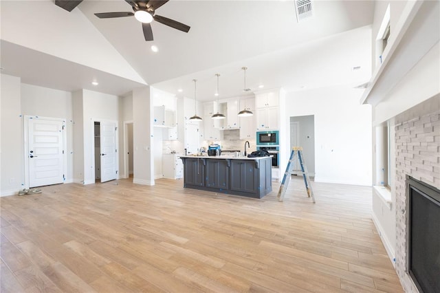 kitchen featuring a stone fireplace, white cabinetry, stainless steel oven, visible vents, and built in microwave