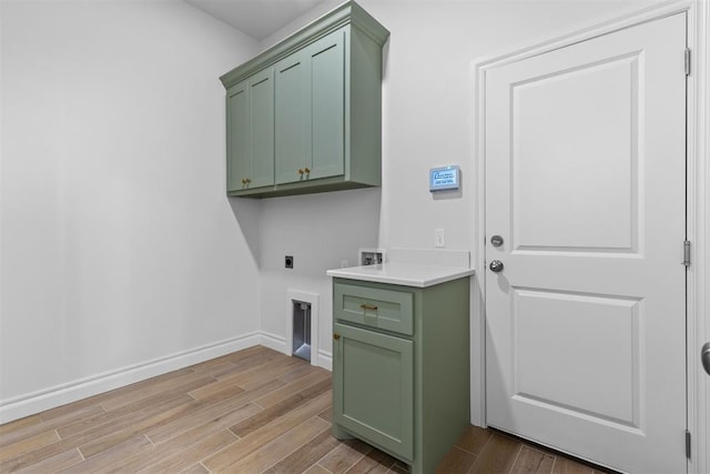 laundry area featuring hookup for an electric dryer, washer hookup, light wood-type flooring, and cabinets