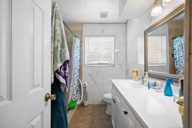 bathroom featuring vanity, curtained shower, toilet, and tile walls