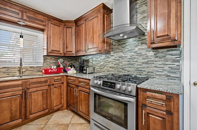 kitchen featuring high end range, decorative backsplash, light stone countertops, wall chimney exhaust hood, and sink