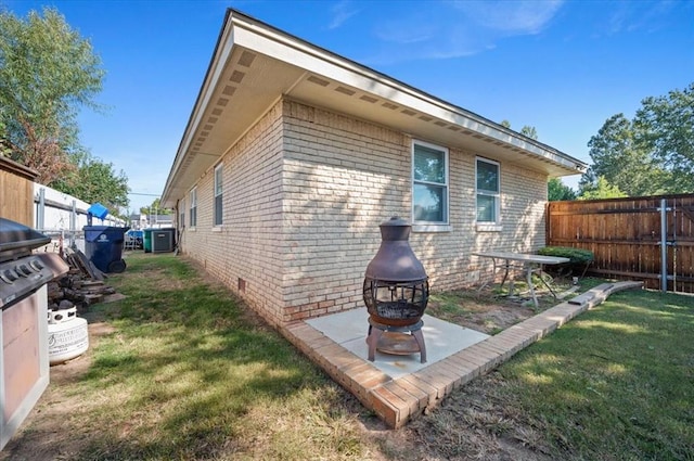 view of side of home featuring a fire pit, central AC unit, and a lawn