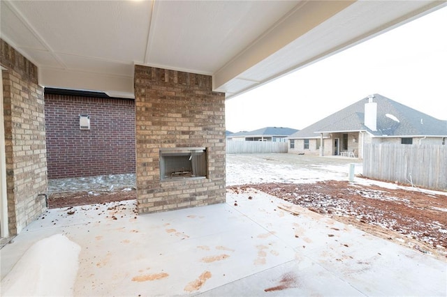 view of patio featuring an outdoor brick fireplace and fence