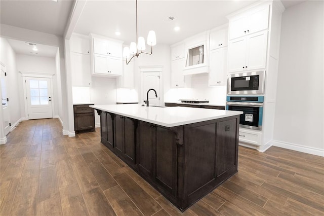 kitchen featuring dark wood finished floors, light countertops, a sink, built in microwave, and oven