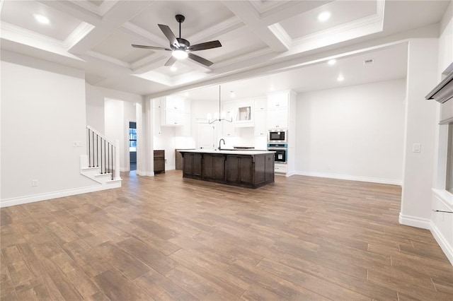 kitchen with light countertops, a ceiling fan, open floor plan, wood finished floors, and built in microwave