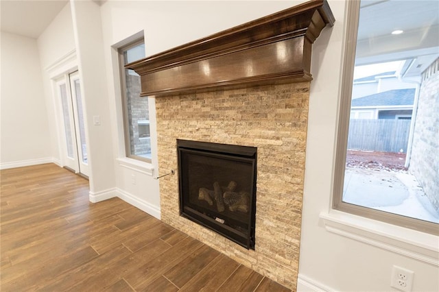 details featuring wood finished floors, a glass covered fireplace, and baseboards