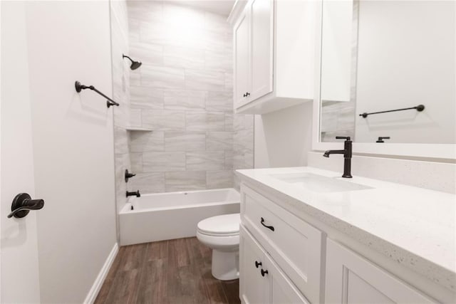 bathroom with toilet, wood finished floors, vanity, baseboards, and shower / bathing tub combination