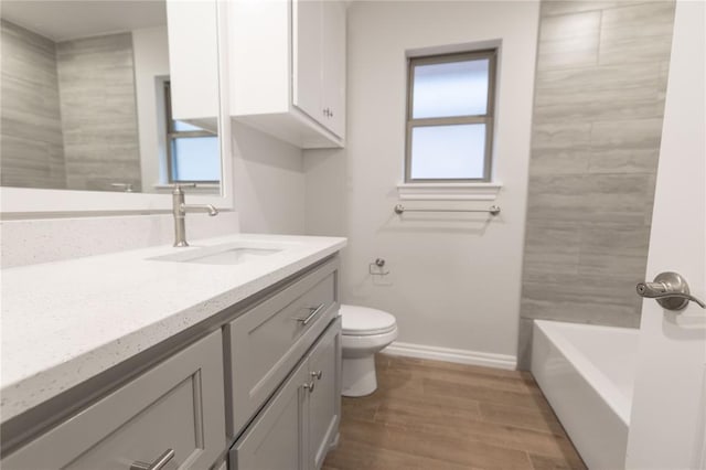 bathroom featuring baseboards, toilet, wood finished floors, and vanity