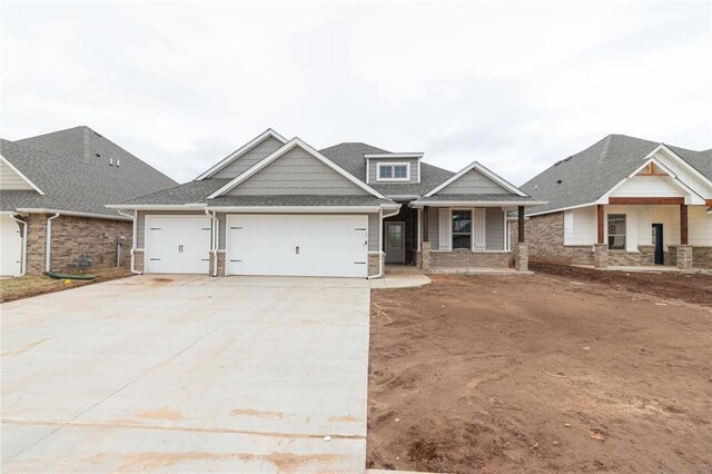 craftsman inspired home featuring an attached garage, a shingled roof, and driveway