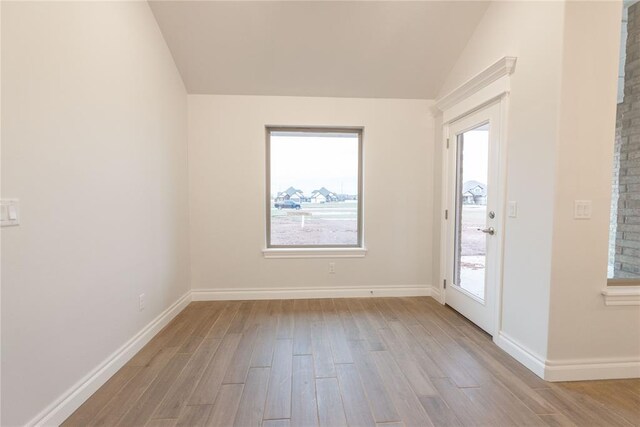 unfurnished room with vaulted ceiling, wood finished floors, and baseboards