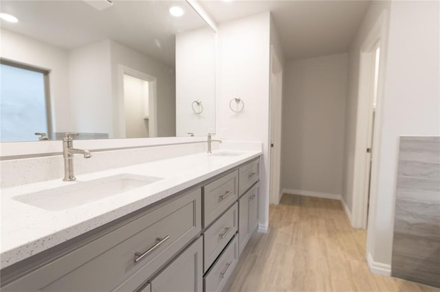 full bathroom with double vanity, wood finished floors, baseboards, and a sink