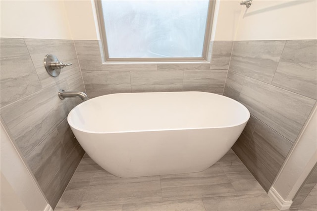 bathroom featuring a freestanding bath and tile walls