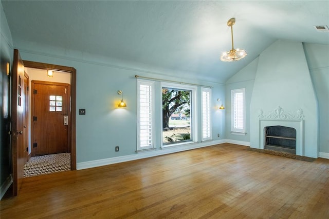 unfurnished living room with wood-type flooring, a large fireplace, vaulted ceiling, and plenty of natural light