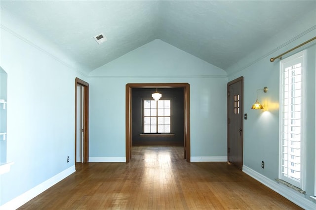 spare room featuring wood-type flooring and vaulted ceiling