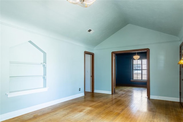 unfurnished room with hardwood / wood-style flooring, built in features, and lofted ceiling