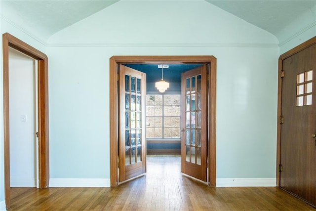 foyer featuring wood-type flooring, lofted ceiling, and french doors