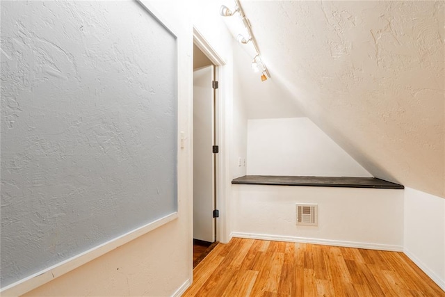 additional living space with wood-type flooring and lofted ceiling