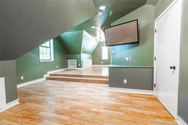 bonus room with vaulted ceiling and light wood-type flooring