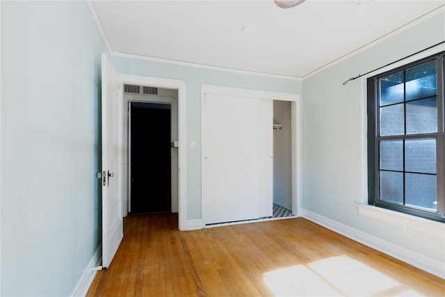 unfurnished bedroom featuring a closet, ornamental molding, and hardwood / wood-style flooring