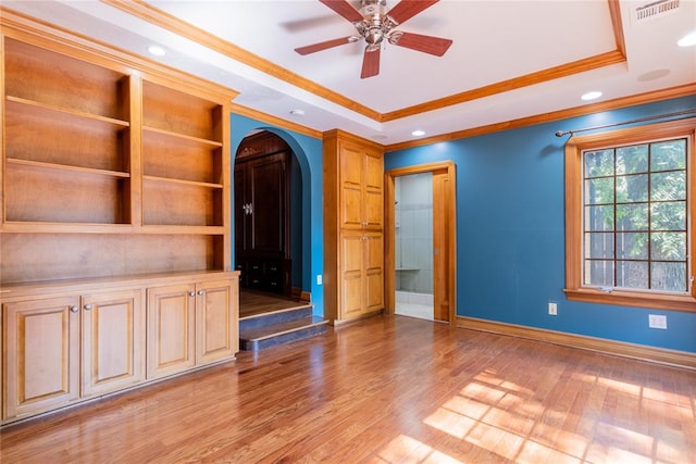 unfurnished living room with a tray ceiling, ceiling fan, light hardwood / wood-style flooring, and crown molding