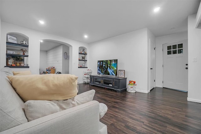 living room featuring built in shelves and dark hardwood / wood-style floors