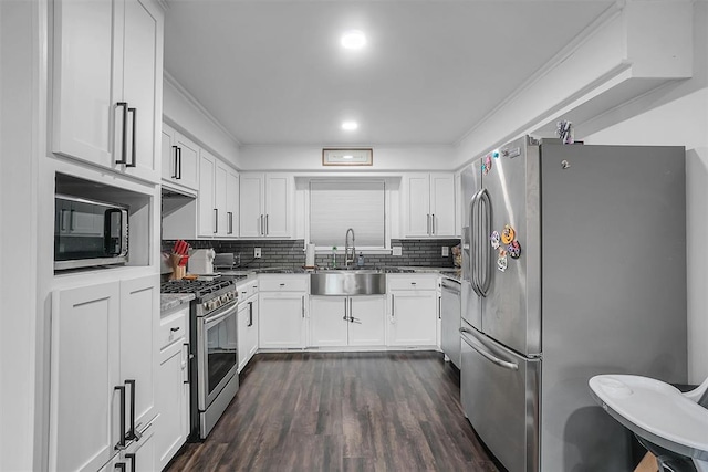 kitchen featuring appliances with stainless steel finishes, backsplash, dark wood-type flooring, sink, and white cabinets