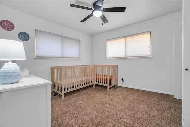 carpeted bedroom with ceiling fan and a crib