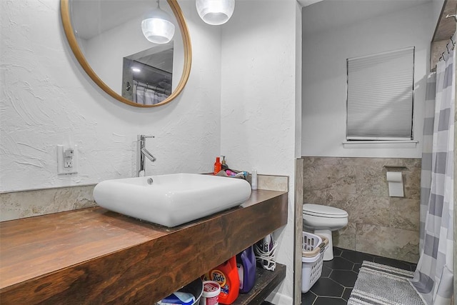 bathroom featuring toilet, tile patterned floors, tile walls, and sink