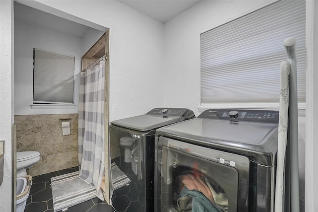 clothes washing area with tile patterned flooring, tile walls, and independent washer and dryer