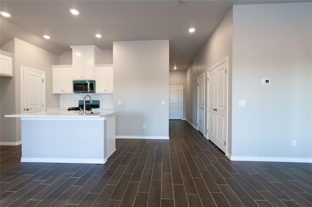 kitchen featuring stove, white cabinetry, light countertops, tasteful backsplash, and stainless steel microwave