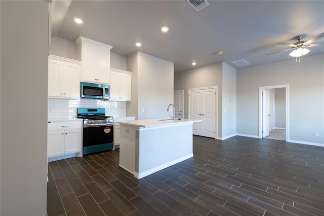 kitchen featuring visible vents, an island with sink, appliances with stainless steel finishes, light countertops, and backsplash