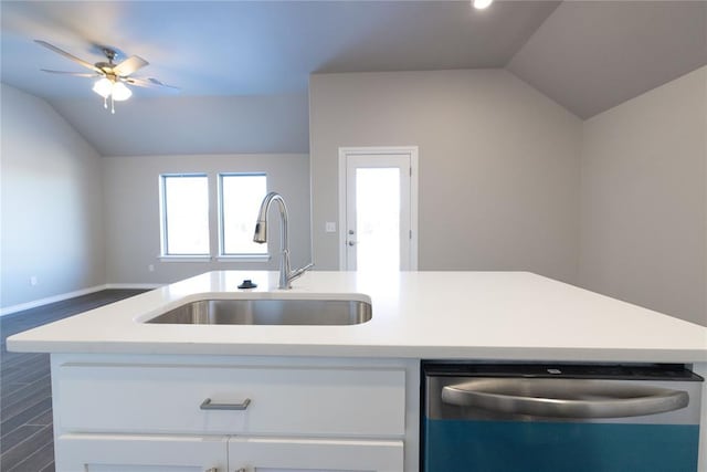 kitchen featuring vaulted ceiling, light countertops, stainless steel dishwasher, white cabinetry, and a sink