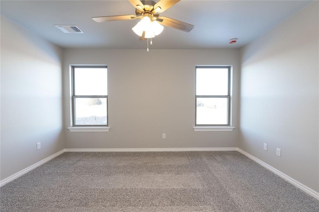 carpeted empty room with baseboards, visible vents, and a ceiling fan