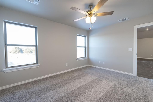 carpeted empty room with a ceiling fan, visible vents, and baseboards