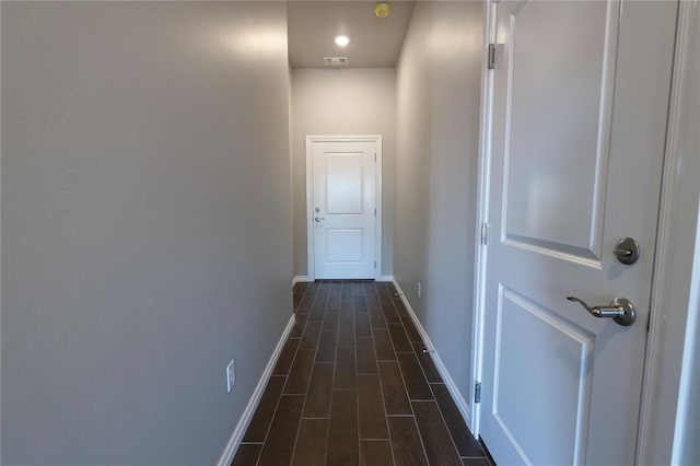 hallway with wood tiled floor, visible vents, and baseboards