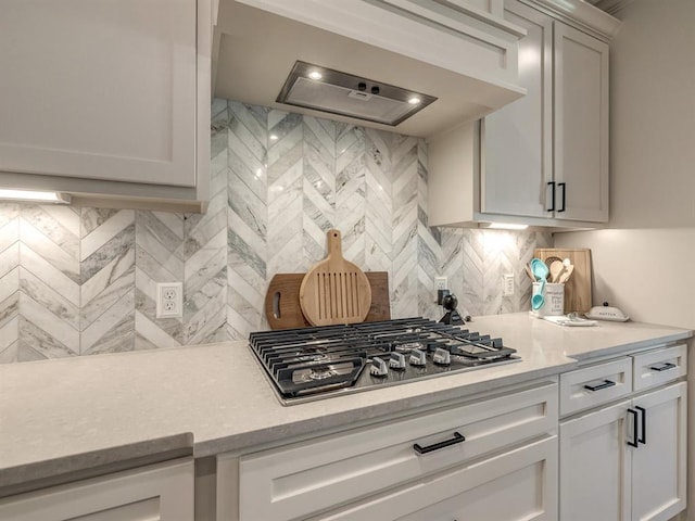 kitchen featuring white cabinets, ventilation hood, stainless steel gas cooktop, and tasteful backsplash