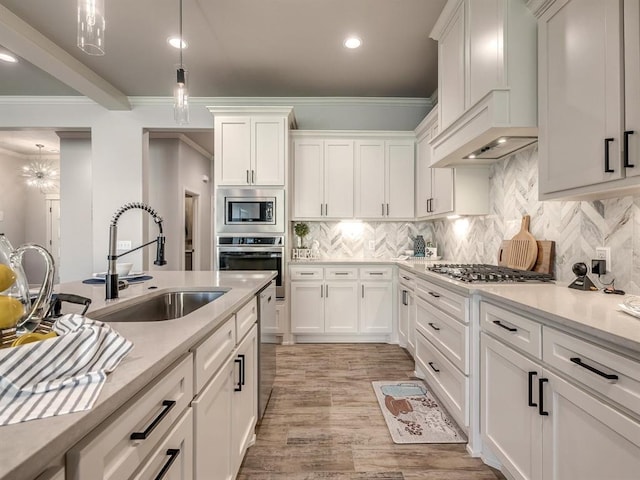 kitchen with sink, light hardwood / wood-style flooring, premium range hood, white cabinets, and appliances with stainless steel finishes