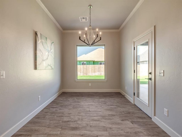 unfurnished dining area with ornamental molding, a chandelier, and hardwood / wood-style flooring