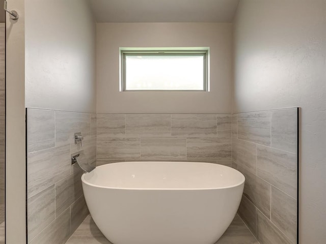 bathroom featuring a tub to relax in and tile walls