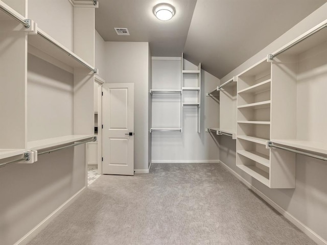 spacious closet featuring light colored carpet and lofted ceiling