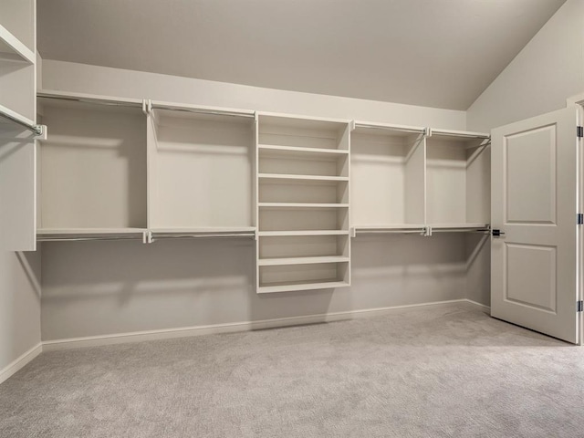 walk in closet with light carpet and lofted ceiling