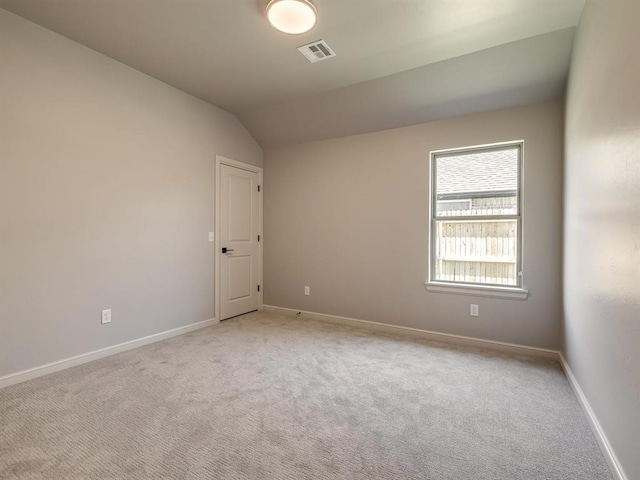 spare room featuring light carpet and lofted ceiling