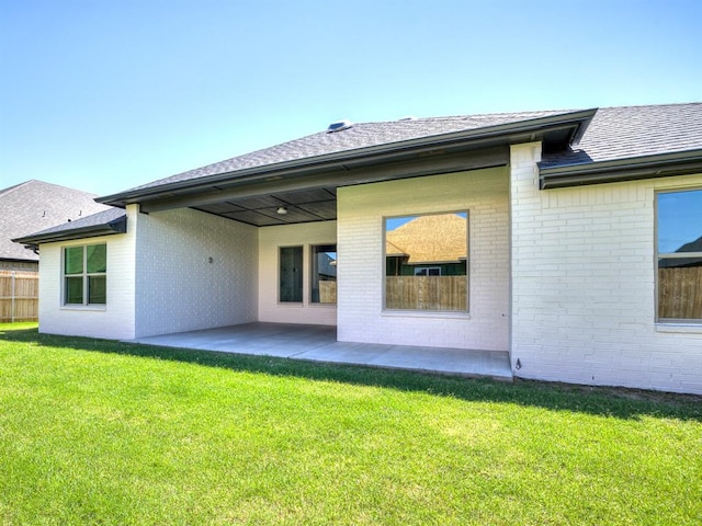 rear view of house featuring a lawn and a patio