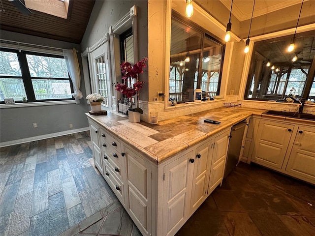 kitchen with sink, stainless steel dishwasher, wooden counters, pendant lighting, and ornamental molding