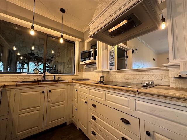 kitchen with premium range hood, tasteful backsplash, black electric cooktop, sink, and decorative light fixtures